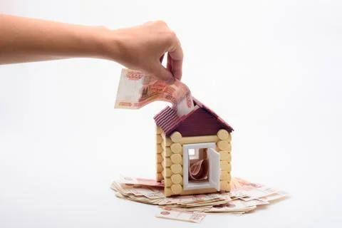 Hand shoves a five thousandth bill into the roof of a house Fotos de archivo