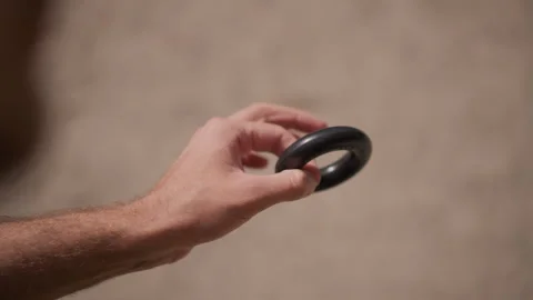 Hand Showcasing Black Grip Ring With Textured Surface And Soft Illumination Stock Footage 329501276