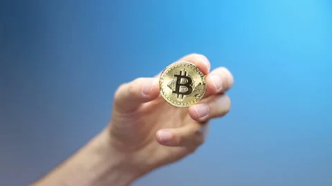 Hand showing from a blur effect a Bitcoin coin. For a new business concept Stock Footage 162028101