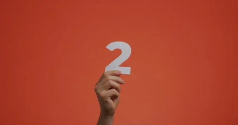 Hand showing number two. Arm with digits, second numeral made of carved paper Stock Footage 157453465
