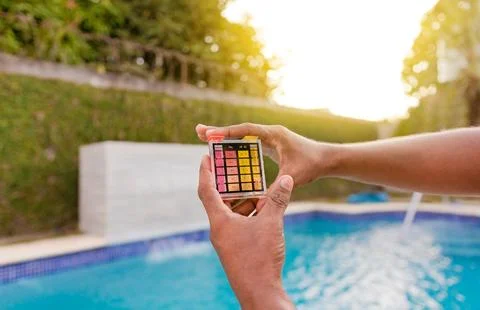 Hand showing water test kit with swimming pool background. Hand holding a p.. Stock Photos