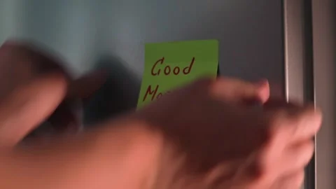 A hand is shown placing a green sticky note on a door with a friendly message. Stock Footage 339096511