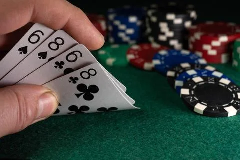 A hand shows four cards with two pairs while colorful poker chips are stack.. Foto stock