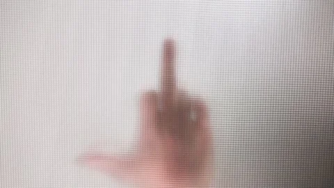 The hand shows the middle finger close-up behind a cloudy opaque glass Stock Footage 220045707