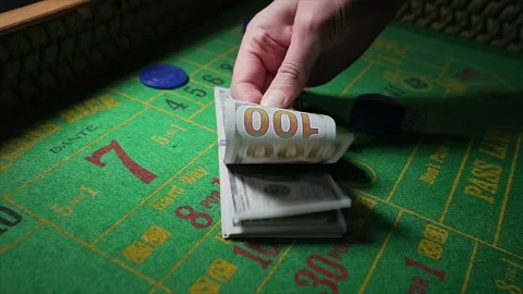 Hand shuffles through stack of hundred dollar bills on craps table Stock Footage 153951962