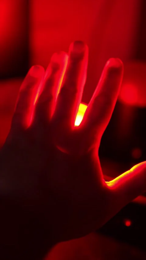 Hand silhouette with bright red glowing light between fingers, dark Stock Footage 332600564