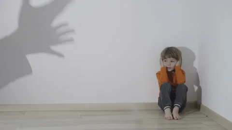 Hand silhouettes reflect on wall arguing child sit in corner, hands cover ears Stock Footage 163763567