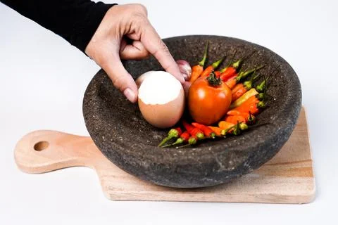 A hand single partially peeled hard-boiled egg inside a rustic stone mortar.. Stock Photos