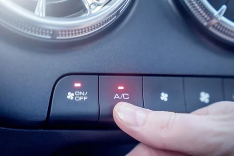 A hand skillfully adjusting the air conditioning button located in a cars cli Stock Photos
