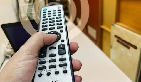 A hand skillfully operates a remote control, symbolizing the ease of channe.. Stock Photos