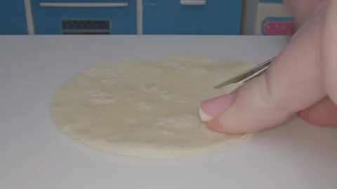 Hand skillfully prepares food in a tiny kitchen using miniature cookware to Video stock 286890044