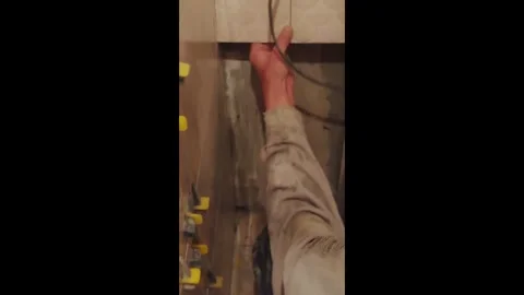 A hand is skillfully working on the intricate electrical wiring located beneath 動画素材 347023909