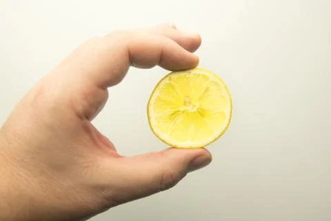 Hand with slice of yellow lemon Stock Photos