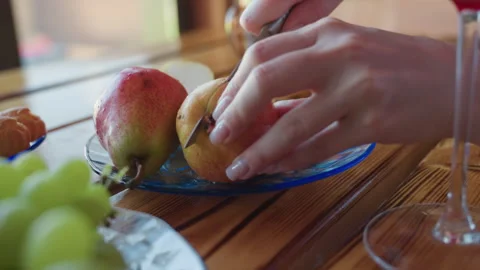 Hand Slices Apple With Knife On Plate Beside Pears In Natural Light Stock Footage 316834597