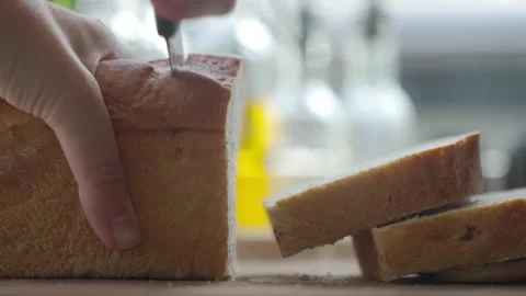 Hand slicing bread with knife, cutting thick pieces from a loaf Stock Footage 337657849