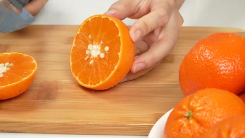 Hand Slicing Fresh Orange in Half with Knife on Cutting Board 4K Stock Footage 319437370