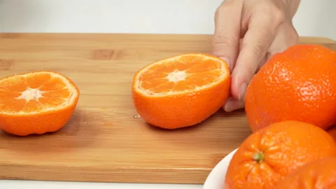 Hand Slicing Fresh Orange in Half with Knife on Cutting Board 4K Stock Footage 319454080
