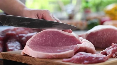 Hand slicing fresh raw meat on a cutting board in the kitchen - slow motion Stock Footage 154600162