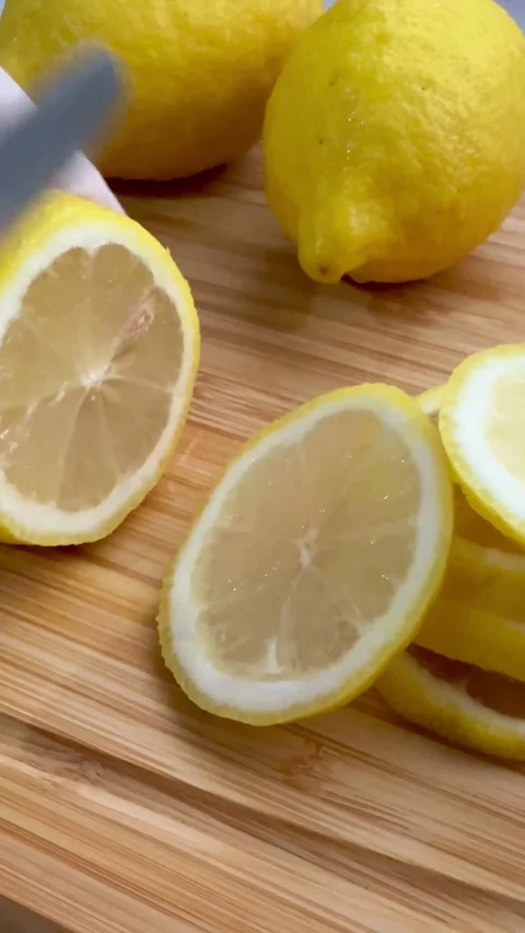Hand slicing a fresh yellow lemon into thin rounds Stock Footage 331974612