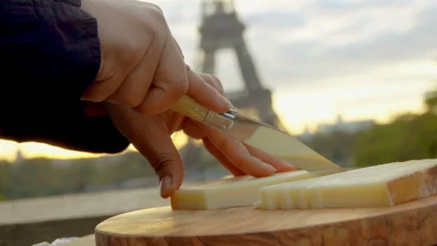 Hand slicing goat cheese on backdrop Eiffel Tower Video stock 123165334