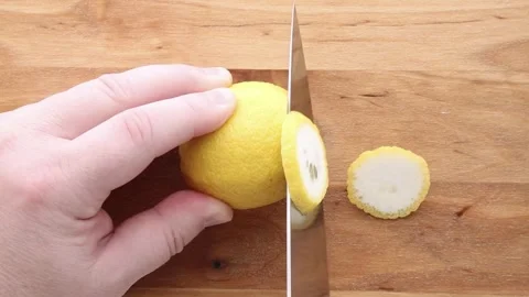 Hand Slicing Lemon Into Thin Rounds On Wooden Cutting Board Video stock 311012428