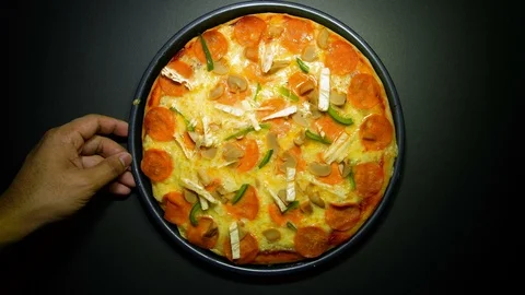 Hand slicing the pizza using circle pizza slicing knife on dark background. pann Stock Footage 103276440