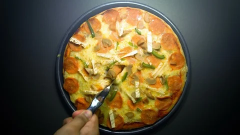 Hand slicing the pizza using circle pizza slicing knife on dark background. zoom Stock Footage 103277035