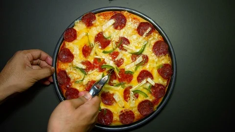 Hand slicing the pizza using circle pizza slicing knife on dark background. zoom Stock Footage 103277602