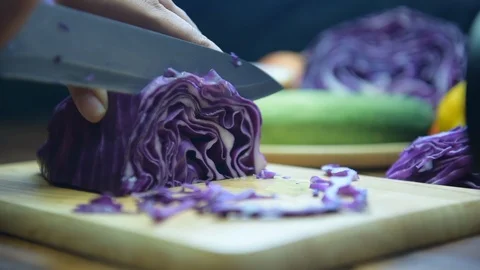 Hand slicing a purple cabbage with a knife. Stock Footage