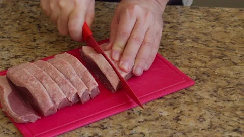 Hand slicing raw meat with a knife for a barbecue Stock Footage 130265880