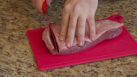 Hand slicing raw steaks with a knife Stock Footage 130265674