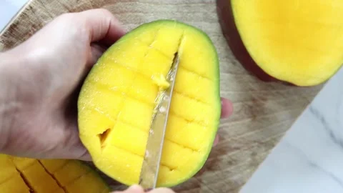 Hand slicing ripe mango fruit over wooden chopping board Stock Footage 285599822