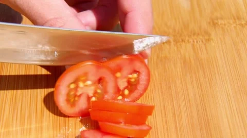 Hand slicing ripe tomato into thin pieces on board Stock Footage 317186085