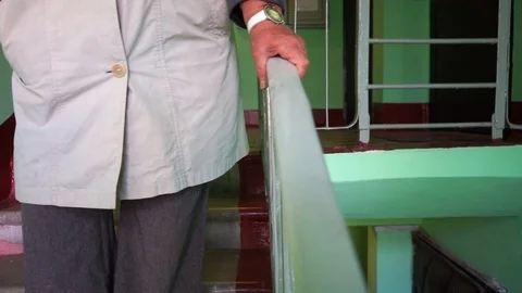Hand slides over the railing, an elderly woman comes down the stairs Stock-Footage 95692859