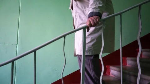 Hand slides over the railing, an elderly woman comes down the stairs Stock Footage 95692869