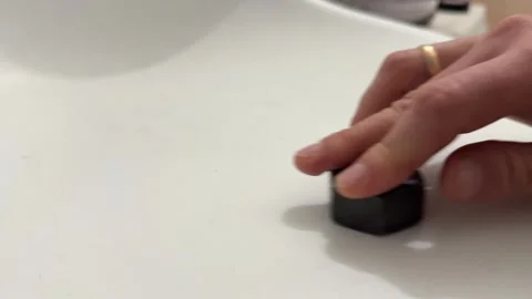 Hand sliding a large plastic nut across a white surface. Close up of moving Stock Footage 336976572