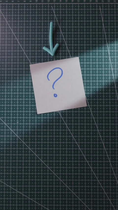 Hand sliding question mark note with arrow on green checkered mat Stockbeeldmateriaal 342818940