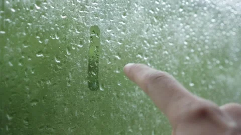 A hand slowly draws a smiling face on misted glass dotted with droplets, adding Stock Footage 322514920