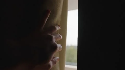 Hand slowly moves and open heavy window curtain letting sunlight in dark room Video stock 221247009