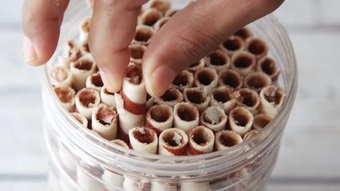 A hand slowly picks up a waffle roll with a brown striped pattern from a tr.. Stock Footage 333033129