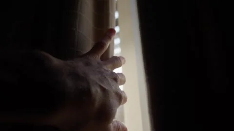 Hand slowly reaching towards a window curtain and open it to reveal sunlight Stock Footage 289416279
