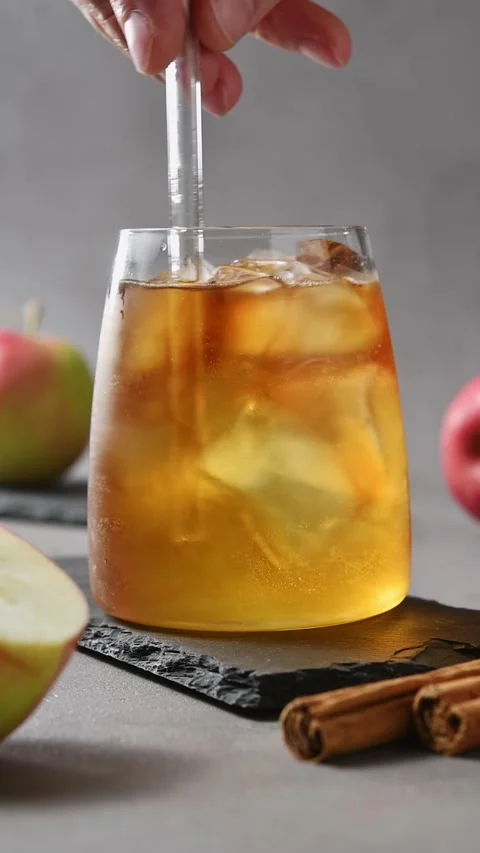 Hand slowly stirs apple cider cold brew tonic with glass straw, mixing coffee Stock Footage 345557165