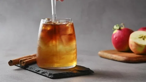 Hand slowly stirs apple cider cold brew tonic with glass straw, blending coffee Stock Footage 345557771