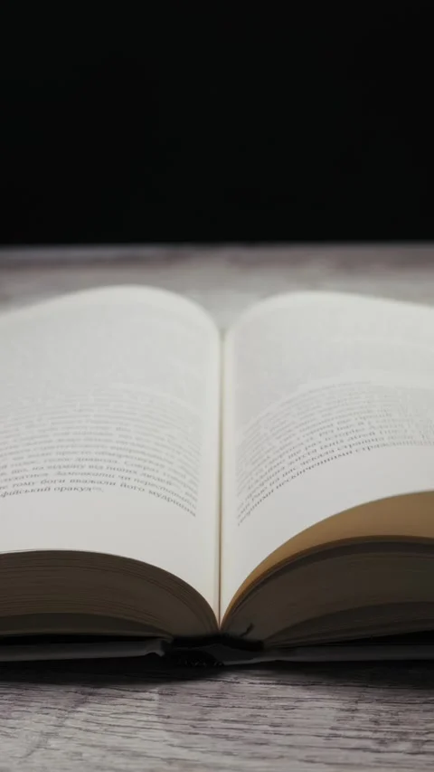 Hand Slowly Turning Pages of an Open Book on a Wooden Table Stock Footage 329682206