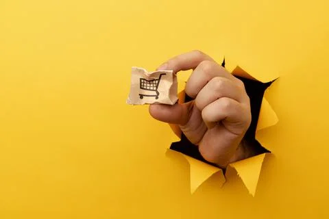 Hand with a small broken delivery box through a yellow paper hole Stock Photos