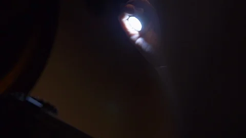 In hand a small LED flashlight.Man turns it on examines object in front him. Stock Footage 105861397