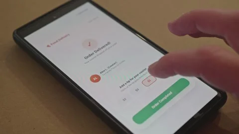 Hand on smartphone adding tip to courier in mobile food delivery application Stock Footage 341569543