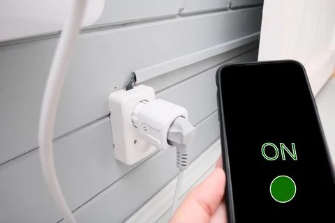 A hand with a smartphone that control and switch wi-fi internet smart socket  Stock Photos