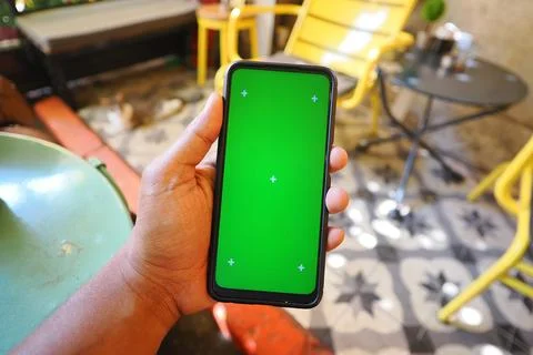 Hand with smartphone on green screen Stock Photos