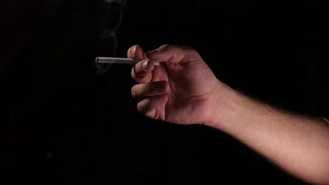 Hand with a smoking cigarette on a black background Stock Footage 172480762